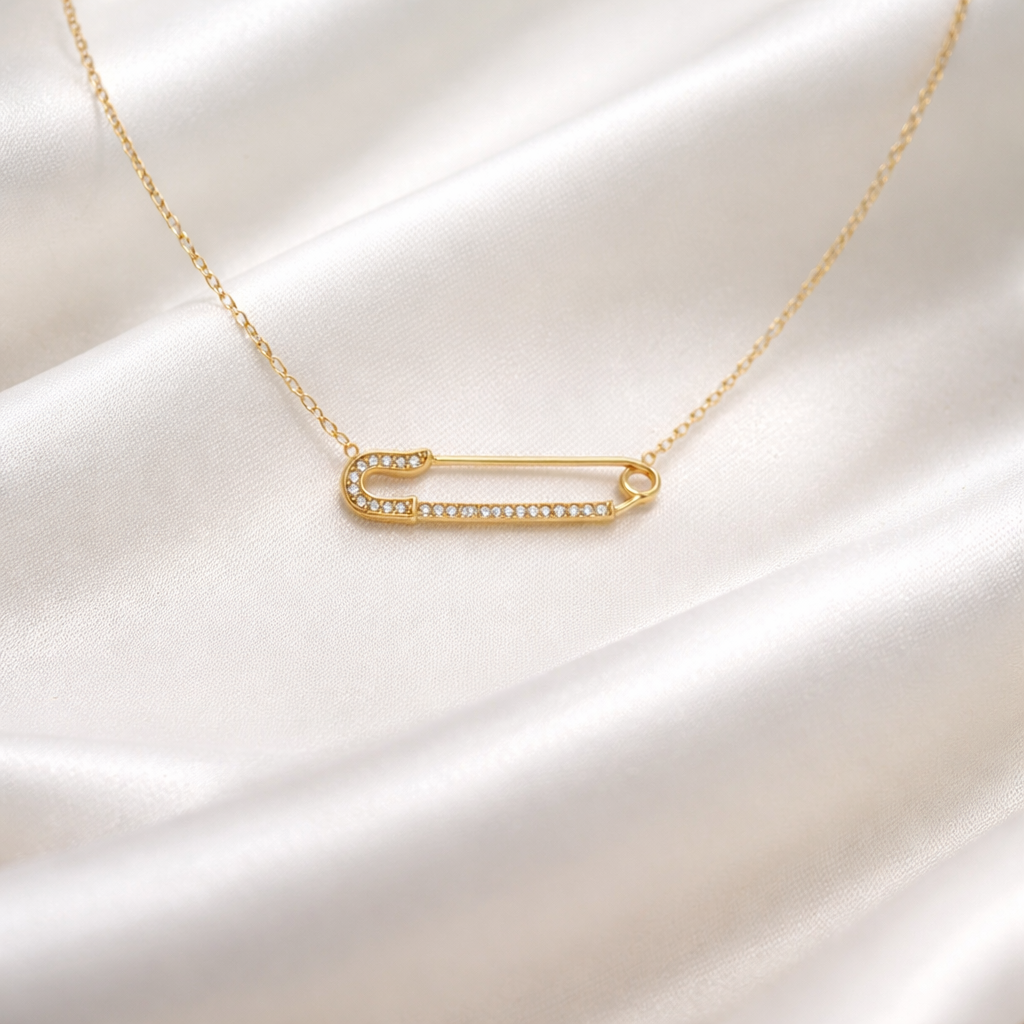 Élan Bar Necklace with a safety pin pendant on a white satin background