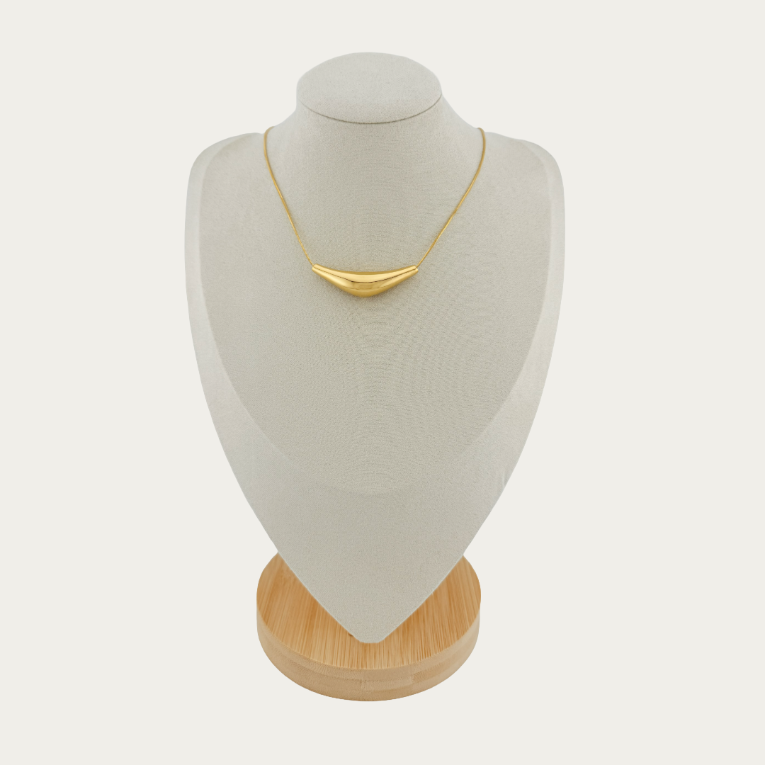 Solace Curve Necklace in gold on a mannequin bust with a wooden base against a white background