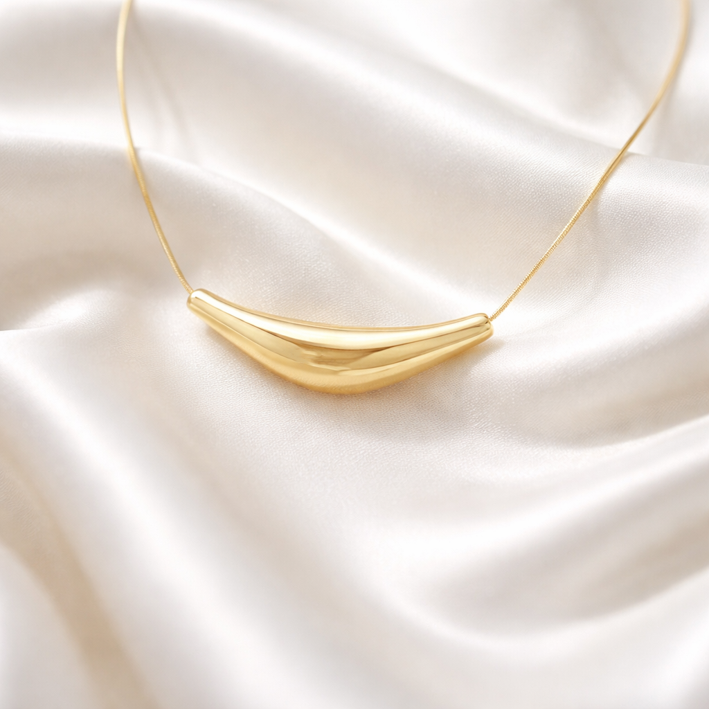 Solace Curve Necklace in gold on a satin surface